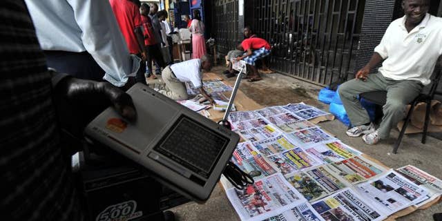 People look at newspaper headlines on a street in Monrovia on October 12, 2011