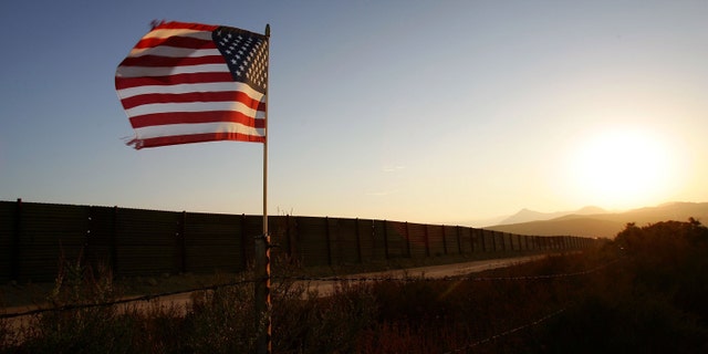 CAMPO, CA - OCTOBER 08: A U.S. flag put up by activists who oppose illegal immigration flies near the US-Mexico border fence in an area where they search for border crossers October 8, 2006 near Campo, California. The activists want the fence expanded into a fully-lit double-fenced barrier between the US (foreground) and Mexico. US Fish and Wildlife Service wardens and environmentalists warn that a proposed plan by US lawmakers to construct 700 miles of double fencing along the 2,000-mile US-Mexico border, in an attempt to wall-out illegal immigrants, would also harm rare wildlife. Wildlife experts say cactus-pollinating insects would fly around fence lights, birds that migrate by starlight in the desert wilderness would be confused, and large mammals such as jaguars, Mexican wolves, Sonoran pronghorn antelope, and desert bighorn sheep would be blocked from migrating across the international border, from California to Texas. (Photo by David McNew/Getty Images)