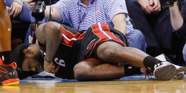 LeBron James, del Heat de Miami, se duele tendido en la duela tras ser impactado por Serge Ibaka en el cuarto periodo del duelo de la NBA frente al Thunder de Oklahoma City, el jueves 20 de febrero de 2014. James recibió el golpe mientras se enfilaba a la canasta. Completó una clavada, pero se fracturó la nariz en la jugada. (Foto AP/Sue Ogrocki)