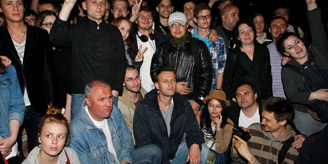 May 8, 2012: Alexei Navalny, at bottom center, a prominent anti-corruption whistle blower and blogger, and opposition leader Sergei Udaltsov, standing at second from left, pose with protesters gathering in the opposite side of the Presidential administrations building in downtown Moscow early Tuesday, a day after Vladimir Putin's inauguration.