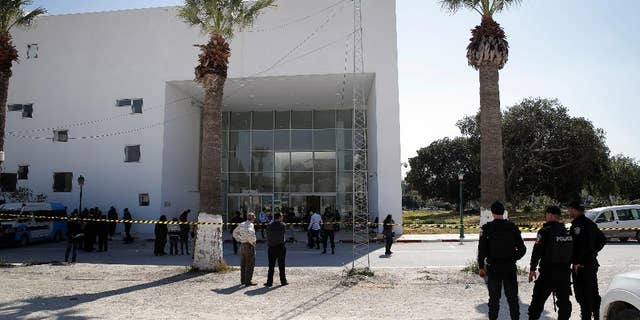 Policemen guard the entrance of the Bardo museum in Tunis, Tunisia, Thursday, March 19, 2015,  a day after gunmen opened fire killing over 20 people, mainly tourists. One of the two gunmen who killed  tourists and others at a prominent Tunisian museum was known to intelligence services, Tunisia's prime minister said Thursday. But no formal links to a particular terrorist group have been established in an attack that threatens the country's fledgling democracy and struggling tourism industry. (AP Photo/Christophe Ena)