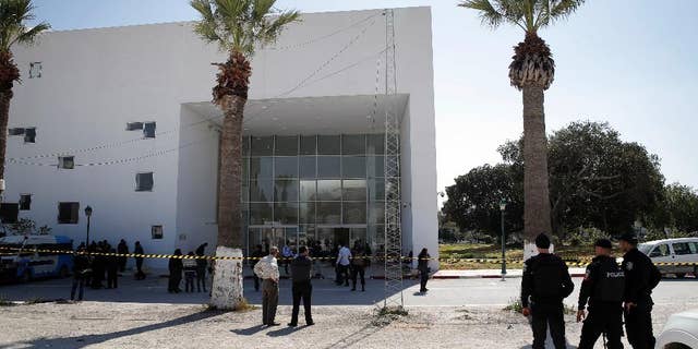 Policemen guard the entrance of the Bardo museum in Tunis, Tunisia, Thursday, March 19, 2015, a day after gunmen opened fire killing over 20 people, mainly tourists. One of the two gunmen who killed tourists and others at a prominent Tunisian museum was known to intelligence services, Tunisia's prime minister said Thursday. But no formal links to a particular terrorist group have been established in an attack that threatens the country's fledgling democracy and struggling tourism industry. (AP Photo/Christophe Ena)