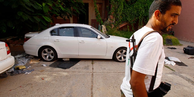 Sept. 1: Libyan rebel stands guards next to the armored car of of the ransacked office of Hannibal, son of Muammar Qaddafi at Bin Achour district inTripoli, Libya.