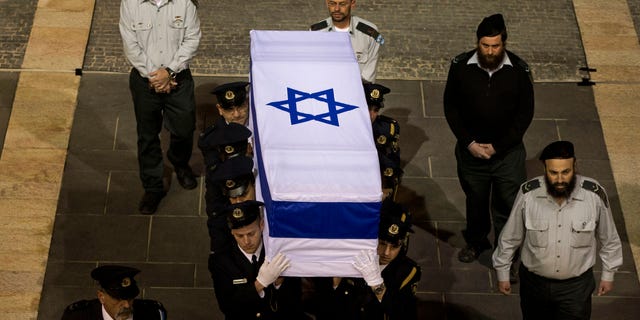 Members of the Knesset guard carry the coffin of late Israeli Prime Minister Ariel Sharon at the Knesset plaza, in Jerusalem, Sunday, Jan. 12, 2014. Israelis from all walks of life flocked to parliament Sunday to catch a glimpse of Ariel Sharon's coffin and pay their final respects to the iconic former prime minister and general. The 85-year-old Sharon died Saturday eight years after a devastating stroke left him in a coma. (AP Photo/Bernat Armangue)