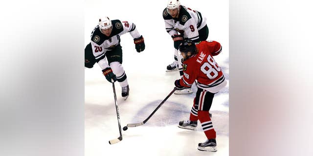 Chicago Blackhawks right wing Patrick Kane (88) shoots against Minnesota Wild defenseman Ryan Suter (20) and center Mikko Koivu (9) during the third period of Game 2 in the second round of the NHL Stanley Cup hockey playoffs in Chicago, Sunday, May 3, 2015. The Blackhawks won 4-1. (AP Photo/Nam Y. Huh)