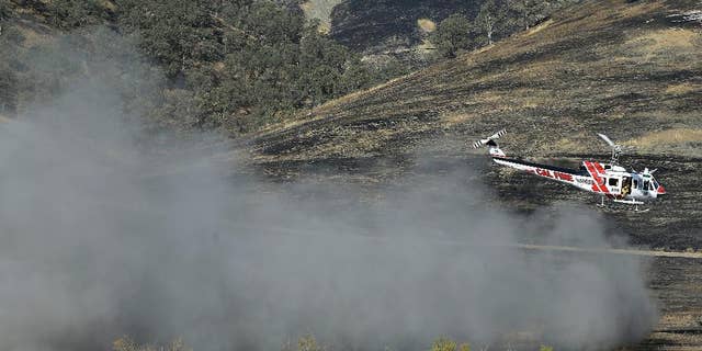 A Cal Fire helicopter flies over the Bear Creek portion of Cache Creek near Clearlake, Calif., Thursday, Aug. 6, 2015. Crews backed by important firefighting resources are gaining ground against a massive Northern California wildfire, but it may be several days before thousands of evacuees can return home, officials said Thursday. (AP Photo/Jeff Chiu)