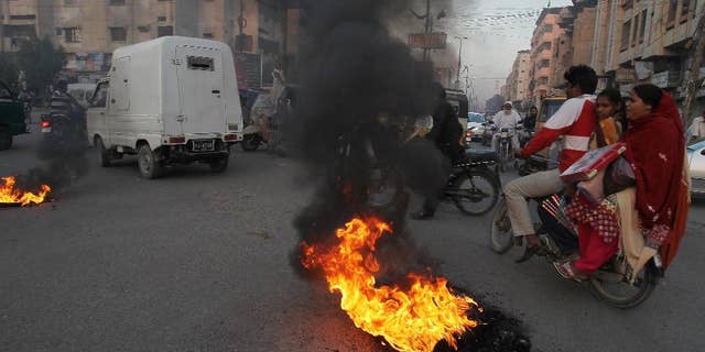 Pakistani protesters burn tires to condemn a blast at a Shiite mosque, Friday, Jan. 30, 2015 in Karachi, Pakistan. The bomb ripped through a mosque in Pakistan belonging to members of the Shiite minority sect of Islam just as worshippers were gathering for Friday prayers, killing dozens of people and wounding many others, officials said. (AP Photo/Fareed Khan)