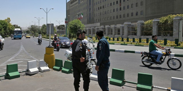 Police officers stand guard as vehicles drive past Iran's parliament building in Tehran, Iran, Thursday, May 8, 2017.