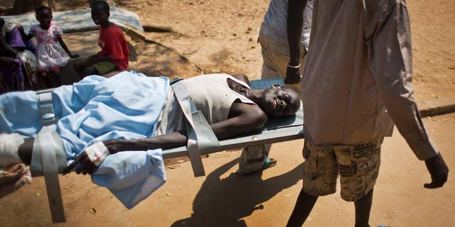 FILE In this Saturday Dec. 28 2013 file photo, a man with a gunshot wound in his leg is carried by stretcher from one ward to another inside the Juba Military Hospital in Juba, South Sudan. One year after mass violence broke out in South Sudan, battles between government forces and rebel fighters continue, and aid officials say the international community must help residents stave off mass hunger. (AP Photo/Ben Curtis, File)