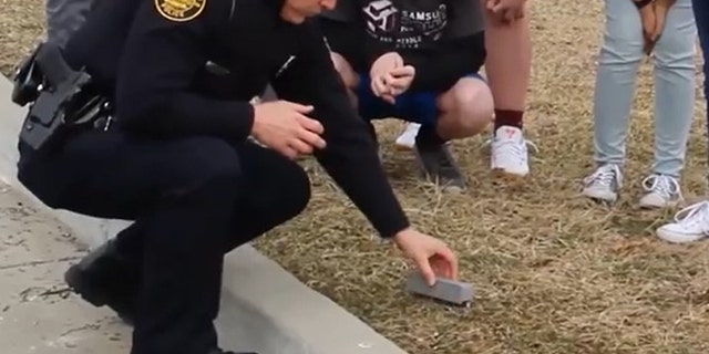 A police officer with the prototype device designed for safely picking up hypodermic needles (Screenshot from Samsung YouTube video)
