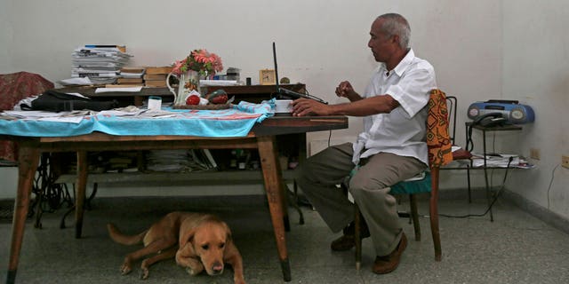 In this Thursday, April 16, 2015 photo, Cuban dissident Hildebrando Chaviano works at his laptop inside his home in Havana, Cuba. Chaviano, a government lawyer turned independent journalist, is one of at least two Cuban dissidents who made it past a first round of voting to become candidates in Sunday's local elections. (AP Photo/Desmond Boylan)