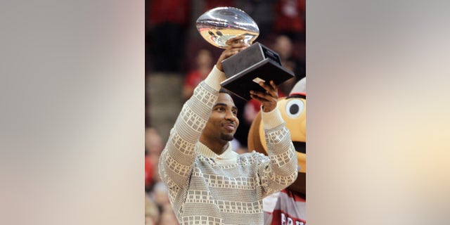 Ohio State quarterback Braxton Miller raises the Silver Football, awarded by the Chicago Tribune to the best football player in the Big 10, during a timeout in an NCAA college basketball game between Ohio State and Northwestern on Wednesday, Feb. 19, 2014, in Columbus, Ohio. (AP Photo/Jay LaPrete)