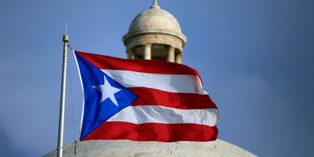 FILE - In this Wednesday, July 29, file 2015 photo, the Puerto Rican flag flies in front of Puerto Ricoâs Capitol as in San Juan, Puerto Rico. On Monday, April 11, 2016, Puerto Rico released a new proposal to restructure part of its $70 billion debt to buy time to implement a fiscal growth plan as multimillion-dollar payments loom for a U.S. territory facing dwindling cash reserves. (AP Photo/Ricardo Arduengo, File)