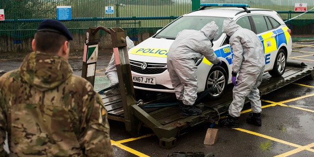 In this image dated Friday March 9, 2018, and issued Saturday March 10, 2018, by Britain's Ministry of Defence, showing troops in protective gear as they work to remove a contaminated police car from the Accident and Emergency entrance at the District Hospital in Salisbury, England.
