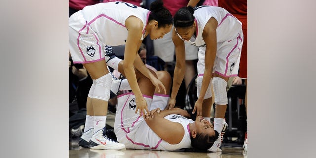 Connecticut's Kaleena Mosqueda-Lewis holds her arm after a hard fall to the court as teammates Saniya Chong, left, and Moriah Jefferson, right, look over her during the first half of an NCAA college basketball game on Sunday, Feb. 9, 2014, in Storrs, Conn. (AP Photo/Jessica Hill)