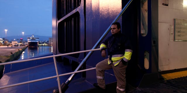 A striking dock workers stands at the entrance of an idle ferry, at the port of Piraeus, near Athens, on Tuesday, Feb. 5, 2013. Greece's conservative-led government used emergency powers to order the strikers back to work after a six-day walkout to protest benefit cuts and austerity measures. Striking unions said they were determined to continue their protest but did not say whether they would directly defy the order. (AP Photo/Petros Giannakouris)