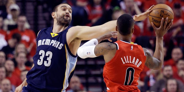 Memphis Grizzlies center Marc Gasol, left, gets a piece of the ball while defending Portland Trail Blazers guard Damian Lillard during the first half of Game 3 of a first-round NBA basketball playoff series in Portland, Ore., Saturday, April 25, 2015. (AP Photo/Don Ryan)