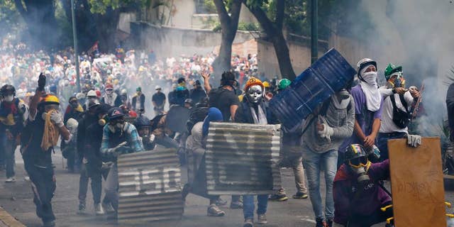 Masked and helmeted demonstrators face off with security forces during an opposition May Day march in Caracas, Venezuela, Monday, May 1, 2017. Venezuelans are taking to the streets in dueling anti- and pro-government May Day demonstrations as an intensifying protest movement enters its second month. (AP Photo/Ariana Cubillos)
