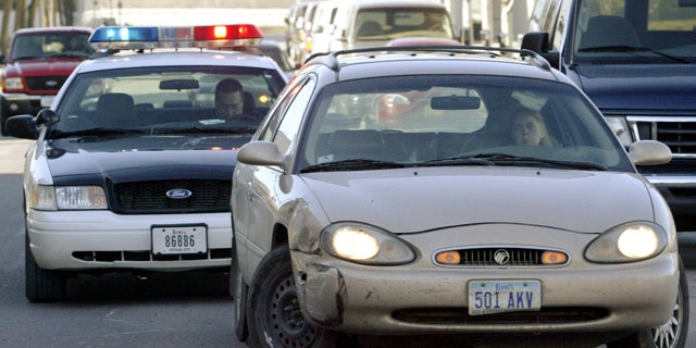 FILE: A motorist whose car has its two front wheels opposing each other is pulled over by a policeman for a moving traffic violation.