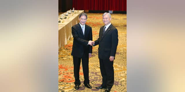 China's Taiwan Affairs Office director Zhang Zhijun, left, and his counterpart Minister Andrew Hsia of the Taiwan's Mainland Affairs Council shake hands in front of the media as they arrive for the start of a two-day cross-strait meeting, Saturday, May 23, 2015, on the outlying island of Kinmen, Taiwan. Zhang is meeting with Hsia to discuss various cross-strait issues, including Taiwan’s interest in joining China-led Asian Infrastructure Investment Bank (AIIB) and the latest trade agreements between both sides. (AP Photo) TAIWAN OUT