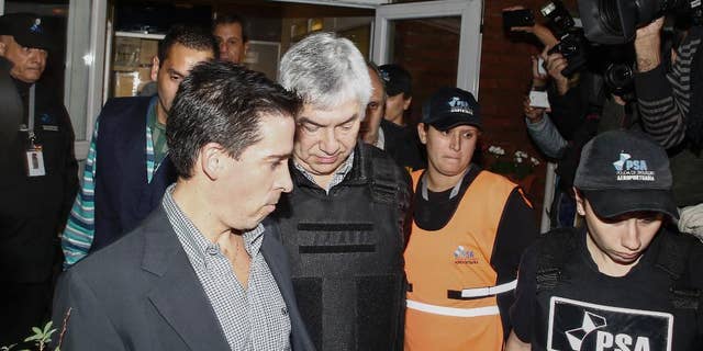 Argentine businessman Lazaro Baez, center, is escorted by police after being arrested as part of an investigation into alleged money laundering, at an airport on the outskirts of Buenos Aires, Argentina, late Tuesday, April 5, 2016. Baez, who got large public works contracts during the Kirchner and Fernandez administrations, is accused of embezzling and laundering millions. He denies any wrongdoing. (AP Photo/Agustin Marcarian)