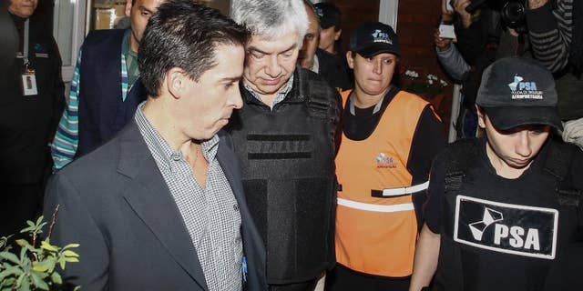 Argentine businessman Lazaro Baez, center, is escorted by police after being arrested as part of an investigation into alleged money laundering, at an airport on the outskirts of Buenos Aires, Argentina, late Tuesday, April 5, 2016. Baez, who got large public works contracts during the Kirchner and Fernandez administrations, is accused of embezzling and laundering millions. He denies any wrongdoing. (AP Photo/Agustin Marcarian)