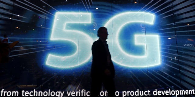 FILE: A visitors walks past a 5G sign during Mobile World Congress in Barcelona last year. The technology is seen as a "key area of competition" internationally.
