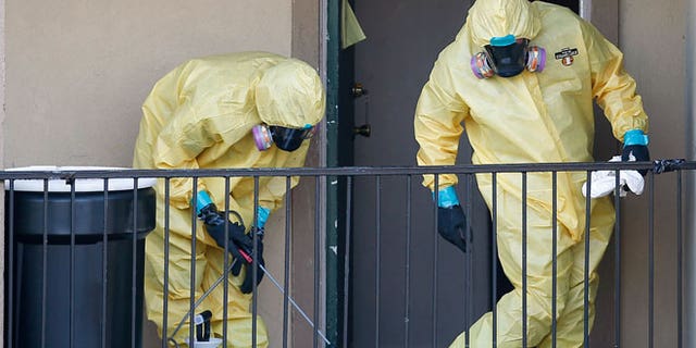 Workers in hazardous material suits clean up after removing the contents of the apartment unit where Thomas Eric Duncan, the first Ebola patient in the U.S., had been staying in Dallas, Texas, October 6, 2014.