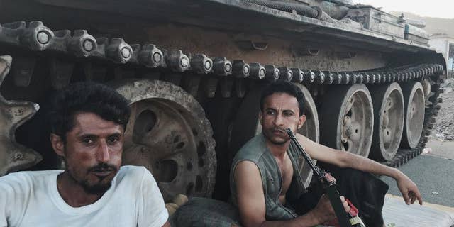 FILE - In this March 21, 2015, photo, Members of a militia group loyal to Yemen's President Abed Rabbo Mansour Hadi, known as the Popular Committees, chew qat as they sit next to their tank, guarding a major intersection in Aden, Yemen. Once hailed by President Barack Obama as a model for fighting extremism, the U.S. counterterrorism strategy in Yemen has all but collapsed as the country descends into chaos, according to U.S. and Yemeni officials. (AP Photo/Hamza Hendawi, File)