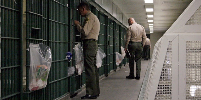 FILE - In this Oct. 3, 2012, file photo, Los Angeles County Sheriff's deputies inspect a cell block at the Men's Central Jail in downtown Los Angeles. The nationâs largest sheriffâs department agreed to federal court oversight and will adopt a new use-of-force policy to settle a class-action lawsuit brought by jail inmates who said they were beaten by guards. The agreement, in effect a consent decree, was approved Tuesday, Dec. 16, 2014, by the Los Angeles County Board of Supervisors. It is the latest in several efforts to reform the scandal-plagued department beset with allegations of rampant abuse by deputies, costly lawsuits and federal convictions of deputies for obstructing an FBI probe into jail beatings. (AP Photo/Reed Saxon, File)