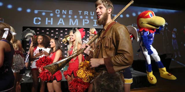 Michael Garcia, dressed as West Virginia's mountaineer mascot, caries a musket after posing for a photo with cheerleaders and mascots at the Big 12 Conference NCAA college football media days in Dallas, Tuesday, July 22, 2014. (AP Photo)