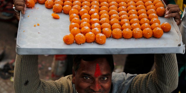 A man carries sweets to distribute as India’s main opposition Bharatiya Janata Party (BJP) supporters celebrate the party’s victory in various state Assembly elections in Allahabad,India , Sunday, Dec. 8, 2013. BJP, the main Hindu nationalist party, appeared to make strong political gains in four heartland states Sunday, as preliminary results showed the ruling Congress party sidelined in a race seen as a test before next year's general election. (AP Photo/Rajesh Kumar Singh)