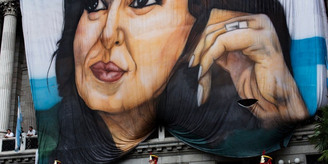 Soldiers of the Granaderos de San Martin regiment stand guard below a giant portrait of Argentina's President Cristina Fernandez hanging outside Congress during the inauguration of the 2015 legislative year in Buenos Aires, Argentina, Sunday, March 1, 2015. In her speech to Congress, Fernandez said prosecutor Alberto Nisman, who had accused her of a criminal cover-up, had also praised her. Nisman was found dead Jan. 18, hours before he was to meet legislators to elaborate on his allegations. (AP Photo/Rodrigo Abd)