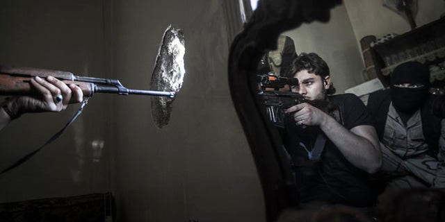 FILE 2012: A rebel sniper aims at a Syrian army position, seen with another rebel fighter reflected in a mirror, in a residential building in the Jedida district of Aleppo, Syria.