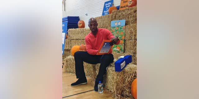 Retired NBA basketball player Chauncey Billups reads "It’s the Great Pumpkin, Charlie Brown" to students at Fairview Elementary in Denver on Monday, Oct. 27, 2014. The NBA season is about to tip off and for the first time in nearly two decades, Billups won't be taking the court. (AP Photo/Pat Graham)