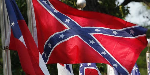 FILE - In this July 19, 2011 file photo, Confederate battle flags fly in Mountain Creek, Ala. The House has voted to ban the display of the Confederate flag on flagpoles at Veterans Administration cemeteries. The 265-159 vote would block descendants and others seeking to commemorate veterans of the Confederate States of America from flying the Confederate Battle Flag over mass graves, even on days that flag displays are permitted. (AP Photo/Dave Martin, File)