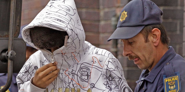 South African Xolile Mngeni, left, accused of taking part in the shooting death of Swedish Anni Dewani is led out of the court building by a police man at Cape Town, South Africa, Tuesday, Sept 20, 2011. Two South Africans allegedly hired by a British newlywed to kill his Swedish bride on their honeymoon in Cape Town will have their case heard by a higher court, a judge ruled Tuesday. At a brief hearing at a magistrate's court, Mziwamadoda Qwabe, 25, and Xolile Mngeni, 23 were ordered to appear before the High Court on Feb. 10. (AP Photo/Schalk van Zuydam)