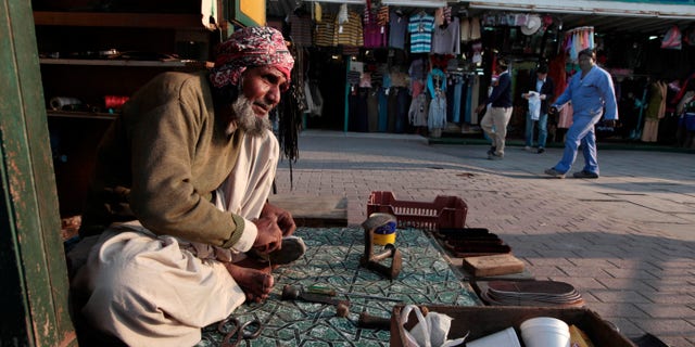 FILE - In this Thursday, Jan. 20, 2011 file photo, a migrant worker repairs shoes at his stall in Doha, Qatar. Dozens of migrant workers hired to do construction work on a prominent skyscraper in Qatar are running low on food after working for almost a year without pay, a leading rights group said on Wednesday, Dec. 18, 2013. (AP Photo/Saurabh Das, File)