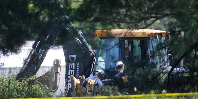 Members of an FBI evidence response team look over an area being cleared in Oakland Township, Mich., Tuesday, June 18, 2013 where officials continue the search for the remains of Teamsters union president Jimmy Hoffa, who disappeared from a Detroit-area restaurant in 1975. (AP Photo/Carlos Osorio)