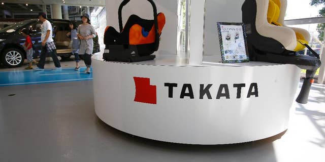 In this Wednesday, May 4, 2016 photo, a family walk by child seats manufactured by Japanese auto parts maker Takata Corp. at an automaker's showroom in Tokyo. Takata, which also makes seat belts, is expecting a loss instead of a profit for the fiscal year that ended in March because of ballooning costs from a massive global air-bag recall. Tokyo-based Takata, which is set to give its earnings report Wednesday, May 11, said Monday, May 9, it is projecting an annual net loss of 13 billion yen ($120 million). (AP Photo/Shizuo Kambayashi)