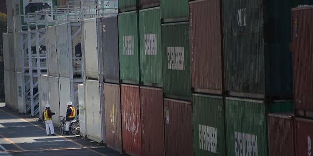FILE - In this Feb. 19, 2015 file photo, port workers chat next to a pile of cargo at a container terminal in Tokyo. Japan posted its first monthly trade surplus in nearly three years in March thanks to falling import costs from cheaper oil prices, along with a modest recovery in exports. The Finance Ministry said Wednesday, April 22, 2015 that preliminary data showed a 14.5 percent drop in imports in March from a year earlier, to 6.7 trillion yen ($55.6 billion). Exports climbed 8.5 percent from a year earlier to 6.9 trillion yen ($57.9 billion), leaving a surplus of 229.3 billion yen ($1.9 billion). (AP Photo/Eugene Hoshiko, File)