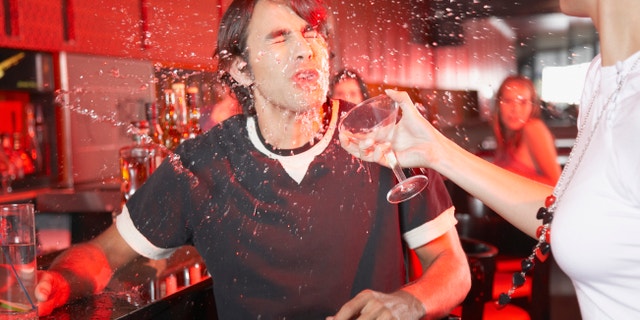 Woman in nightclub throwing beverage in man's face