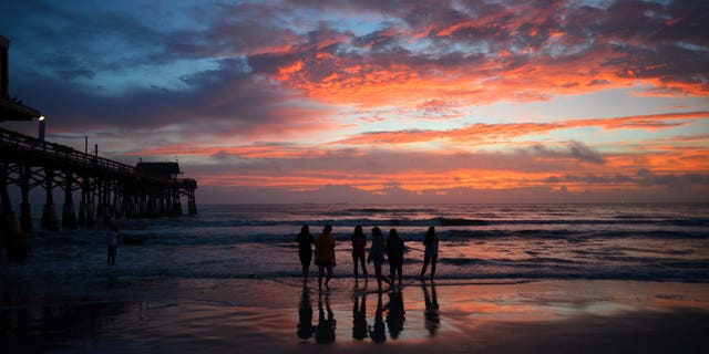 A group of Disney cast members watch the first sunrise of the new year by the Cocoa Beach Pier, Fla., Friday, Jan. 2016. (Malcolm Denemark/Florida Today via AP) MANDATORY CREDIT
