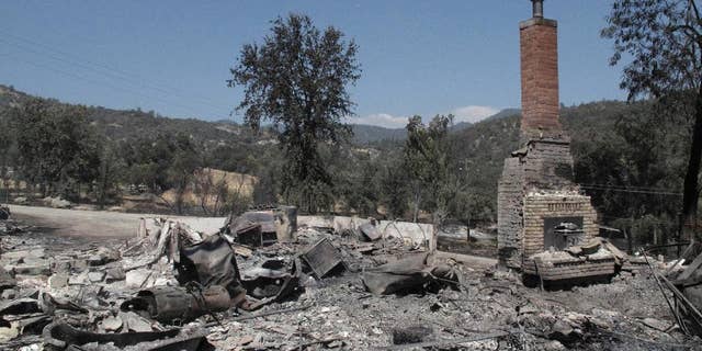 A chimney stands amid the remains of a burnt structure near Oakhurst, Calif., on Tuesday, Aug. 19, 2014. A wildfire that forced about 1,000 people from their homes in the foothills near Yosemite National Park held steady Tuesday as humidity and calmer winds aided the fight against the second blaze around the park in recent weeks. (AP Photo/Scott Smith)