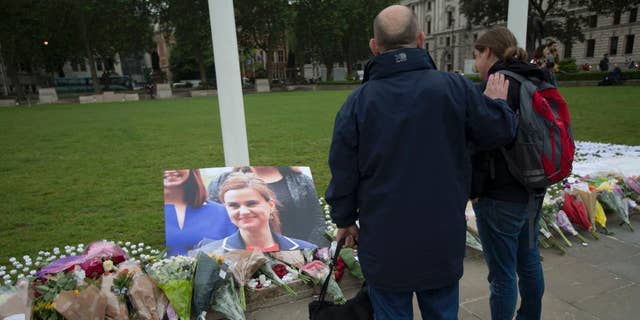 FILE - In this Friday, June 17, 2016 file photo, people look at tributes for Jo Cox, the 41-year-old British Member of Parliament shot to death yesterday in northern England, on Parliament Square outside the House of Parliament in London. Thomas Mair goes on trial, Monday Nov. 14, 2016, accused of murdering lawmaker Jo Cox, who was slain in the street a week before Britain's EU referendum in June. (AP Photo/Matt Dunham, File)