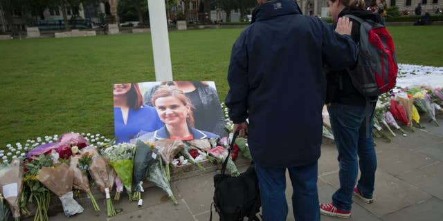 FILE - In this Friday, June 17, 2016 file photo, people look at tributes for Jo Cox, the 41-year-old British Member of Parliament shot to death yesterday in northern England, on Parliament Square outside the House of Parliament in London. Thomas Mair goes on trial, Monday Nov. 14, 2016, accused of murdering lawmaker Jo Cox, who was slain in the street a week before Britain's EU referendum in June. (AP Photo/Matt Dunham, File)