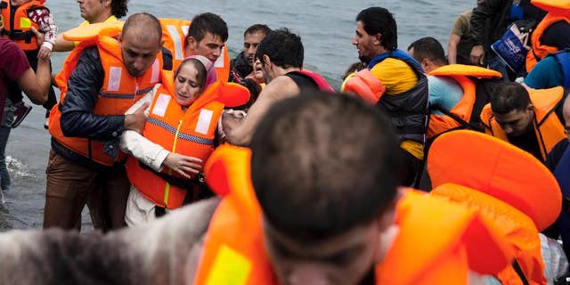 Syrian refugees arrive on the shores of the Greek island of Lesbos after crossing the Aegean Sea from Turkey on a inflatable dinghy , Tuesday, Sept. 22, 2015. More than 260,000 asylum-seekers have arrived in Greece so far this year, most reaching the country's eastern islands on flimsy rafts or boats from the nearby Turkish coast. (AP Photo/Petros Giannakouris)