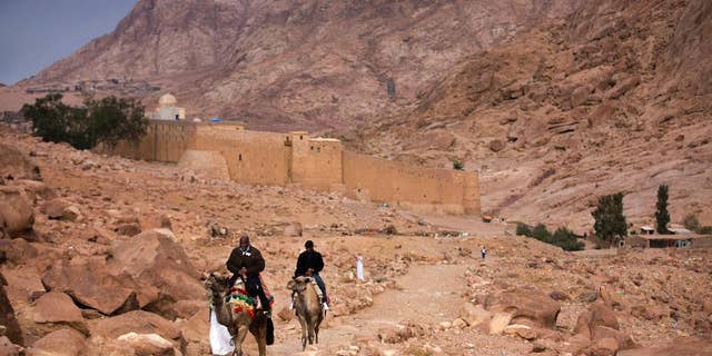 FILE -- In this Dec. 9, 2013 file photo, visitors leave Saint Catherine's Monastery on camels, in Saint Catherine, Egypt. The Islamic State extremist group said Tuesday, April 18, 2017, that its militants carried an attack on a police checkpoint near the famed Monastery in Sinai, which Egyptian security authorities said killed one policeman and wounded four. The attack on the monastery, built in the 6th century and a popular site for tourists visiting the Red Sea resorts along Sinai's southern coast, comes just over a week after suicide bombers attacked two churches in the Nile Delta city of Tanta and the coastal city of Alexandria, killing 45 people on Palm Sunday. (AP Photo/Hiro Komae, File)