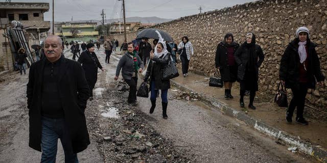 Saturday, December 24, 2016: Christians walk in the rain to attend Christmas Eve's Mass in the Assyrian Orthodox church of Mart Shmoni, in Bartella, Iraq.
