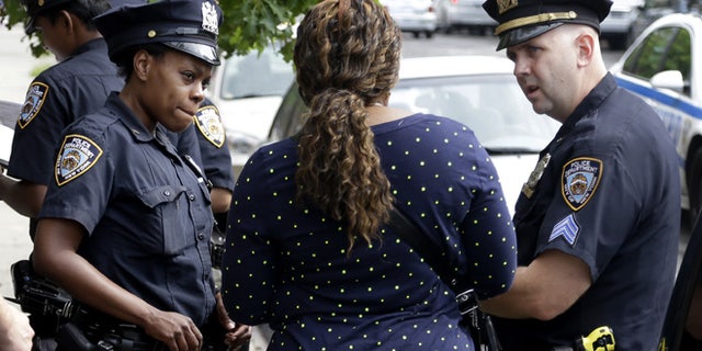 Police officers talk with a woman who had her phone stolen in the Brownsville section of Brooklyn, New York, Tuesday, Aug. 13, 2013. A federal judge's stinging rebuke of the police department's stop-and-frisk policy as discriminatory could usher in a return to the days of high violent crime rates and end New York's tenure as "America's safest big city," Mayor Michael Bloomberg warned. (AP Photo/Seth Wenig)
